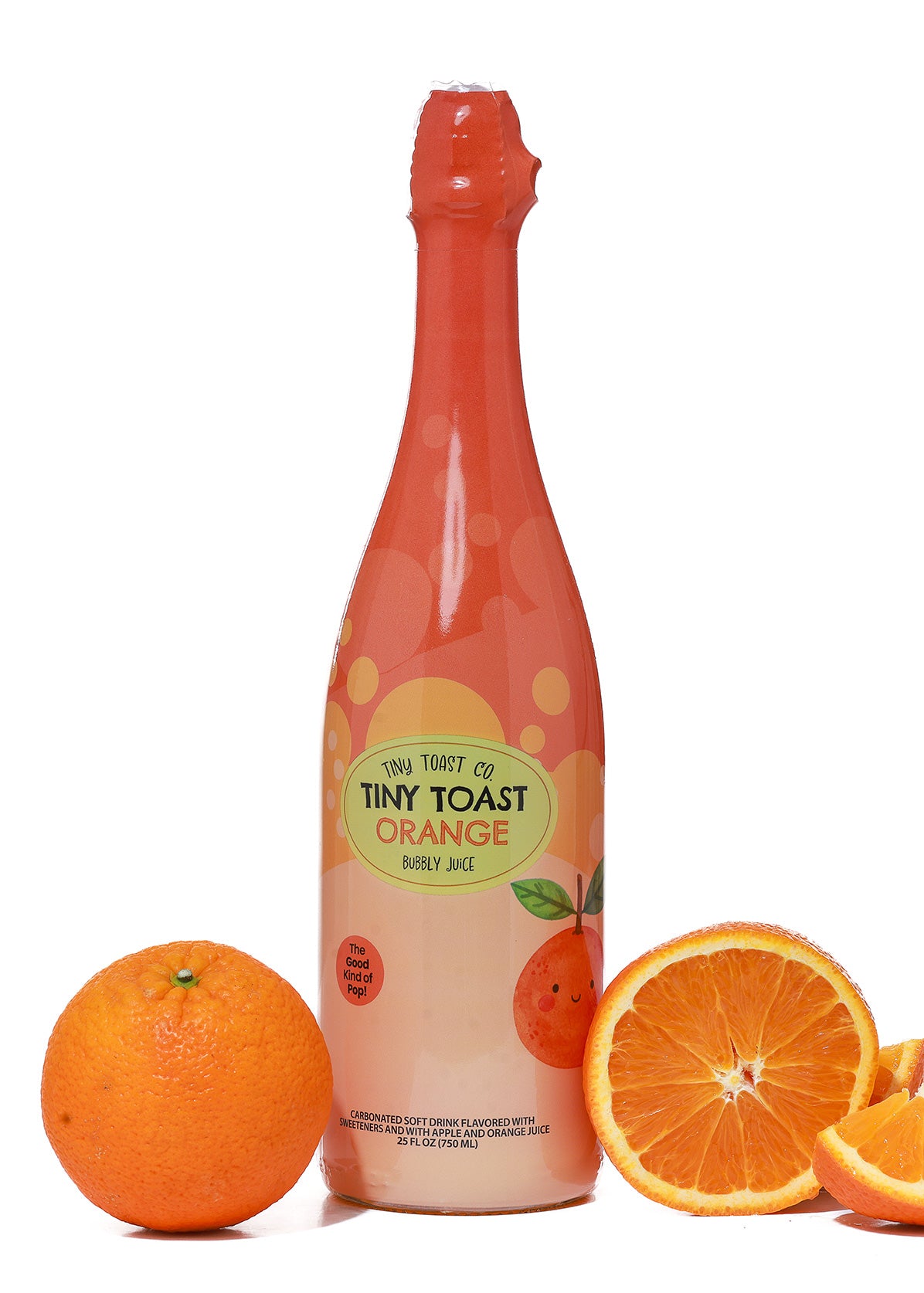 A bottle of Tiny Toast Co. Orange Bubbly Juice stands on a white background, flanked by whole and sliced oranges on both sides.